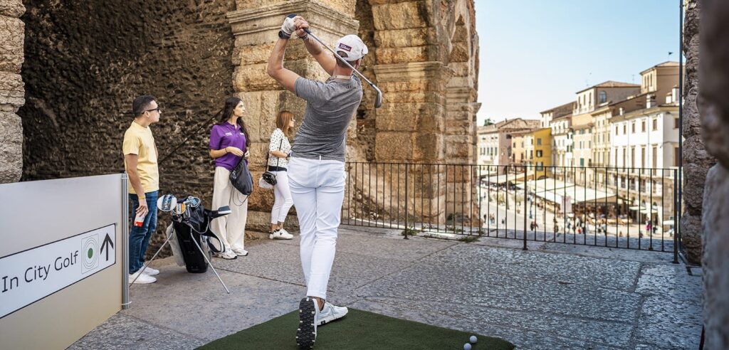 A golfer tees off on the upper ring of the Arena di Verona above Piazza Bra